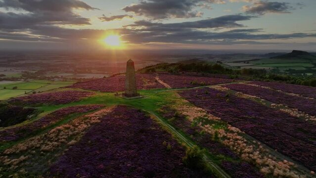 Drone footage of the ling heather bloom in the North York Moors National Park, England. The sun setting behind Captain Cook's Monument, taken with a DJI Mavic 3 Pro.
