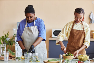 Waist up portrait of two African American women cooking together in kitchen and doing food prep