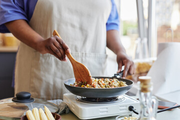 Close up of black woman frying vegetables in kitchen while cooking healthy meal, copy space