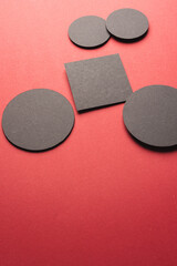 Vertical image of square and circles of black paper with copy space on red background