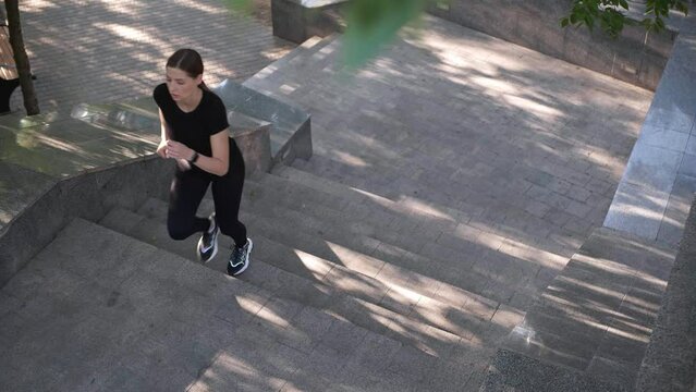 Sporty young woman running up stairs outdoors. Slow motion effect