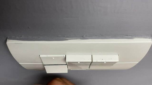 Bangkok, Thailand - Male hand press button to switch off outlet socket power supply close up shot on grey wall