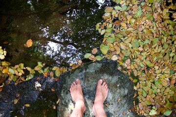 Pieds nus sur une pierre près de la rivière avec feuille