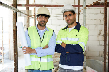 Fototapeta na wymiar portrait workers or architects holding blueprint paper and crossed arms pose at construction site