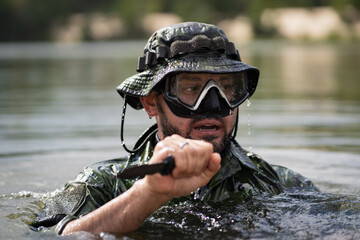 Marine Corps combat swimmer with a knife in his hand in the water, close-up photo.