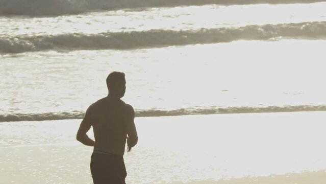 Silhouette of a man jogging on the beach at sunset