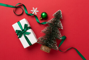 Miniature christmas tree with gift box and decor on color background