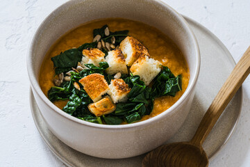 Healthy curry creamy soup with seasonal summer vegetables, sunflower seeds,  croutons, healthy vegan meal in rustic bowl