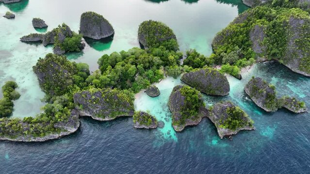 Aerial Tilt Up Shot Of Green Plants On Rock Formations Over Turquoise Sea - Raja Ampat, Indonesia