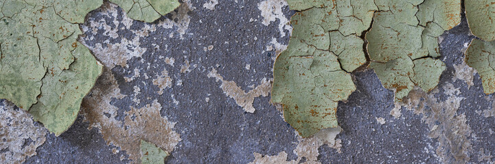 Peeling paint on the wall. Panorama of a concrete wall with old cracked flaking paint. Weathered rough painted surface with patterns of cracks and peeling. Wide panoramic grunge texture for background