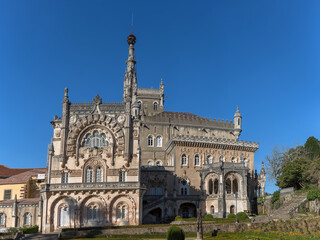 Fototapeta na wymiar Full view of the back facade of the Bussaco Palace, Romantic palace in Neo-Manueline style monument, romantia« classic gardens and blue sky, in Portugal