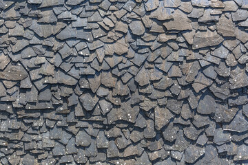Detailed view of wall texture randomly lined with slate panels, typical and traditional shale stone material, used as external waterproof cladding in construction