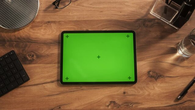 Top Down View of a Tablet Computer with Mock Up Green Screen Display. Static Footage of a Device Lying Horizontally on a Wooden Office Table. Template for Online Tutorials and Creative Content