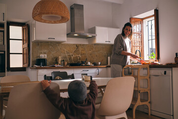 Smiling mother cooking meal in kitchen with son