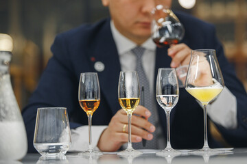 Beginner wine waiter sniffs alcoholic drink during blind tasting. Sommelier school, international...