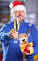Bearded smiling man wearing warm blue sweater with traditional deer hold arm champagne goblet rising toast coming 2018 year with glowing garland background concept closeup