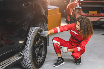 auto service male working in garage car workshop looking check repair broken tire with tablet computer
