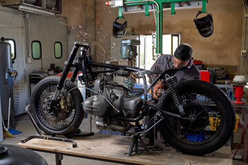 Busy technician with angle grinder repairing motorbike