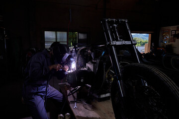 Naklejka na ściany i meble Unrecognizable mechanic repairing motorbike in garage