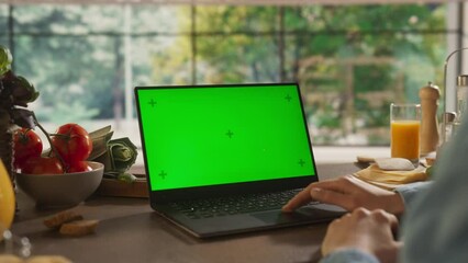 Anonymous Woman In her Kitchen Using a Laptop Computer with Mock Up Green Screen Chromakey Display with Motion Tracker Placeholders. Female Taking Online Cooking Classes, Browsing for Tutorials