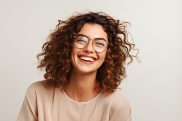 woman wearing glasses laughing and smiling on neutral background