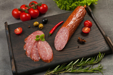 smoked sausage servelat or salami on a dark wooden background