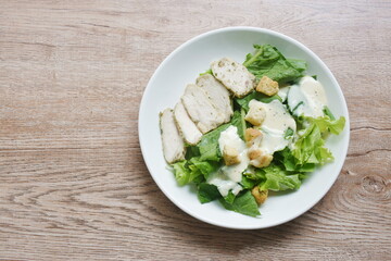 Caesar salad with slice boiled black pepper chicken breast topping crispy bread on plate