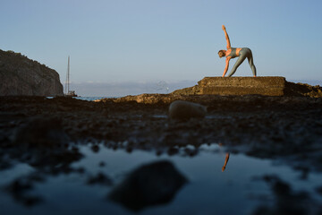 Fototapeta na wymiar Female doing stretching exercise on seashore