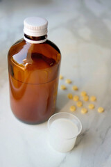 Cough syrup bottle with a glass of syrup and yellow medicine pills