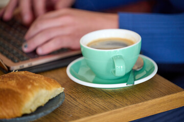 person with coffee and laptop on wooden table