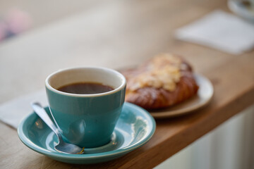 cup of coffee and almond croissant on a wooden table