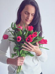 Brunette woman standing with red bouquet of tulips