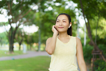 Beautiful smart and good looking Asian adult woman checking on a smartwatch or fitness tracker while practicing running - jogging at the park.