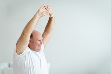 Caucasian white man wake up from the bed in morning and sitting beside the bed then doing a stretch...