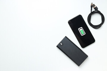 Powerbank, smartphone and cord on white background, space for text
