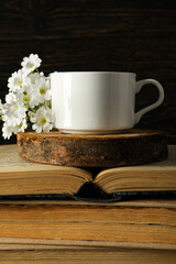 Cup on wooden stand and books on wooden background