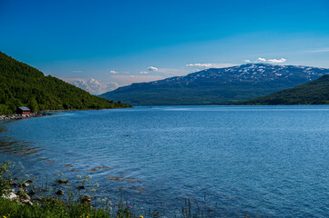 Fototapeta premium Rocky hills covered with snow above sea bay