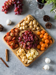Cheese plate with cherry tomatoes and grapes on the New Year's holiday table. Christmas snacks.