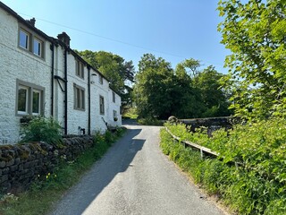 Yorkshire Dales hamlet, view along Stubbing Lane, with cottages, old trees, and a blue sky in, Hubberholme, UK