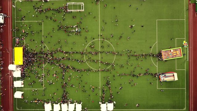 An aerial view showcasing an occasion taking place on a soccer field, with a multitude of people dispersed across the field's expanse.