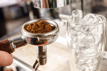 ground coffee with a glass of ice cubes, a barista prepares a coffee drink