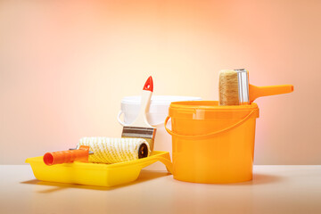 painting tools on orange color background. repair, instruments and materials for painting walls.