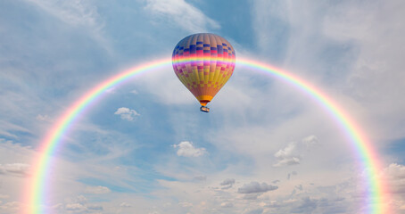 Colorful hot air balloon flying under storm clouds with rainbow