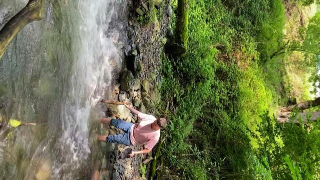 Vertical: man tourist unsafety crossing mountain river in wrong place