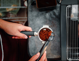 Top view  hand of Coffeemaker's holding a spoon pouring coffee powder grinder grinding coffee pouring into a portafilter