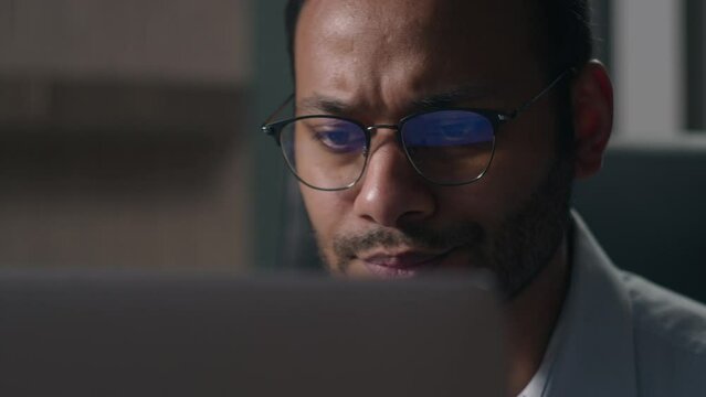 Close up pensive thoughtful male office worker reading bad news in laptop think concerned Indian man American businessman thinking problem solution worry anxiety difficulties business data failure