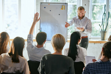 Male speaker giving talk at business meeting. Audience in conference hall. Rear view of businessman...