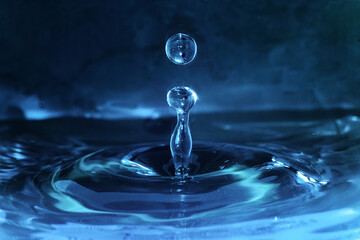 Close up of water drop falling into a sink full of clear and pure water