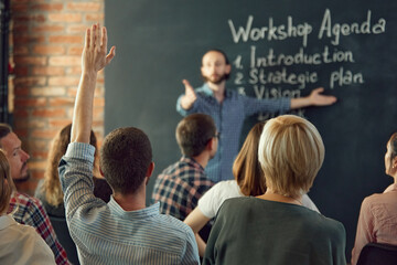 Friendly business coach communicates, teaching with group of adult students at business seminar in...