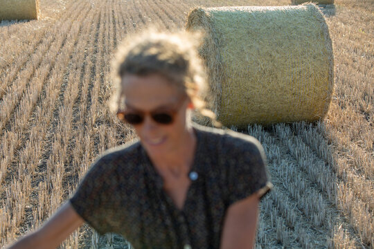 Bales of straw on field stubble at summer, woman on foreground